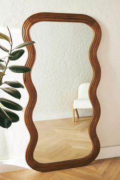 a large mirror sitting on top of a wooden floor next to a potted plant