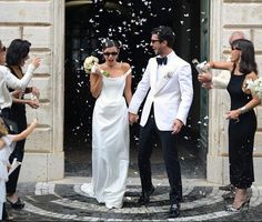 a man and woman walking out of a building with confetti thrown in the air