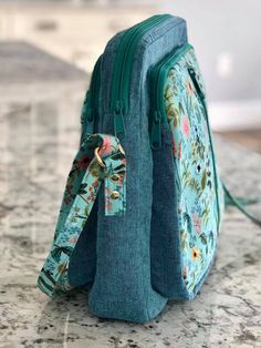 a blue floral purse sitting on top of a marble counter next to a white wall