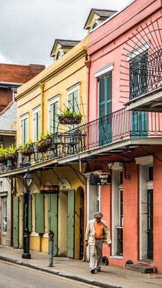 a man walking down the street in front of some colorful buildings with balconies