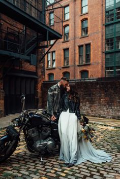 a man and woman standing next to a motorcycle