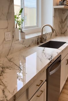 a kitchen with marble counter tops and stainless steel dishwasher in the center island