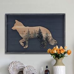 a wooden cutout of a bear is on the wall above a vase with flowers