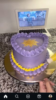 a purple cake sitting on top of a metal platter next to a laptop computer