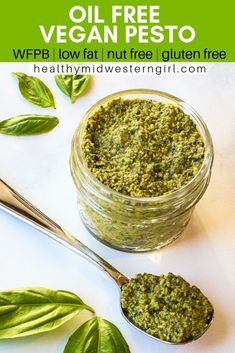 a jar filled with pesto next to two spoons on top of a table