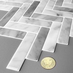 a penny sitting on the floor next to a white tile pattern that looks like it has been made out of marble