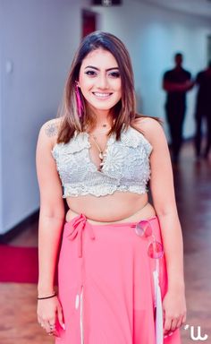 a woman in a pink skirt and crop top posing for the camera with her hands on her hips