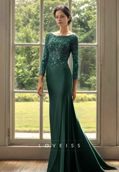 a woman standing in front of a window wearing a green dress with sequins on it