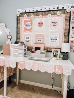 a white desk topped with lots of pink and white items next to a large bulletin board