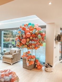 a living room filled with lots of furniture and balloons on top of the floor in front of a large window