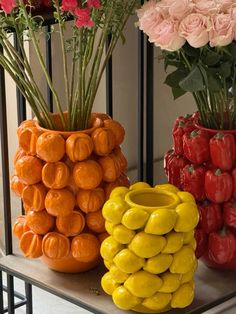 three vases filled with different types of flowers on a shelf next to each other