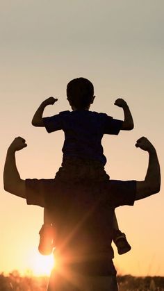 a man holding a child in his arms as the sun sets behind him and there is no image here to provide a caption for