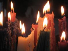 many different colored candles are lit in the dark