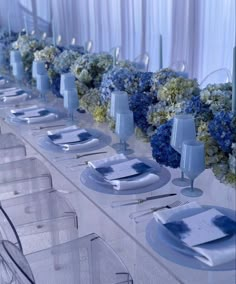 the table is set with blue and white flowers, plates and napkins on it