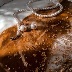 two pearls are attached to a necklace on a rock