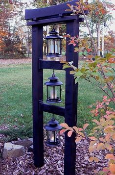 an outdoor shelf with two lanterns on it in the middle of some leaves and grass