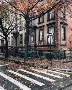 an old brick building with many windows on the side of it and trees in front