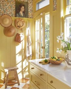 a kitchen with yellow walls and white counter tops, decorated with pictures on the wall