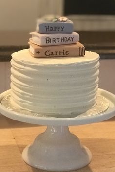 a white cake topped with books on top of a wooden table