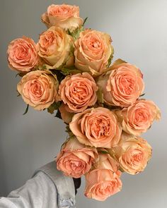 a person holding a bouquet of peach colored roses