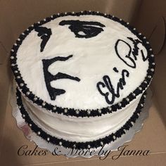 a white cake with black frosting on it in a cardboard box that says elvis