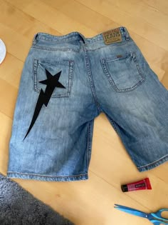 a pair of blue jean shorts with lightning bolt on the side and some scissors next to it