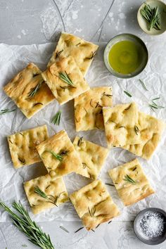 crackers with rosemary and olive oil on parchment paper next to small bowls of dipping sauces