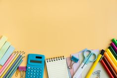 many school supplies are lined up on a yellow background with scissors, pens and pencils