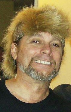 a man with blonde hair wearing a black shirt and a furry hat on his head