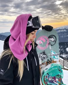 a woman holding a snowboard on top of a mountain