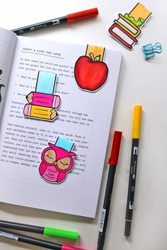 an open book with stickers on it next to markers, pens and crayons