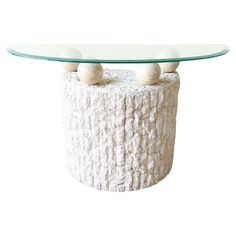 a glass table with two balls on top and a white base in the shape of a log