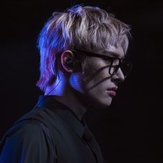 a young man with glasses on his face and hair in the air, looking off to the side