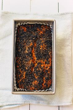 a pan filled with food sitting on top of a white cloth covered table next to a napkin