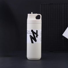 a white water bottle sitting on top of a black table next to a piece of paper