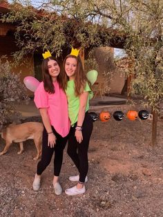 two girls dressed up as tinkerbells in front of a tree and pumpkin patch