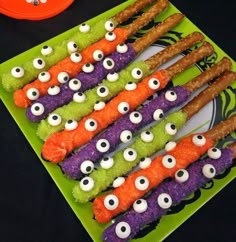 a green plate topped with candy sticks covered in googly eyes and carrots on top of it