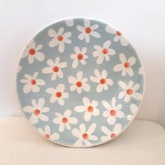 a blue plate with white and orange flowers on it, sitting on a table top