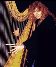 a woman holding a harp and posing for the camera with her hand on it's strings