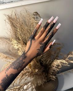 a woman's hand with black and white designs on it, next to some dry grass