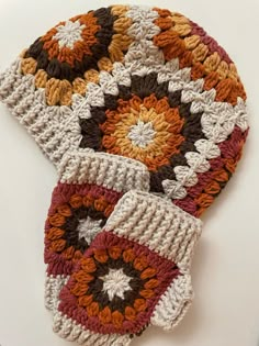 two crocheted hats sitting on top of a white table next to each other