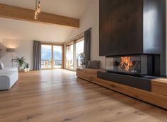 a living room with wood flooring and a fire place in the middle of it