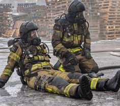 two fire fighters are sitting on the ground