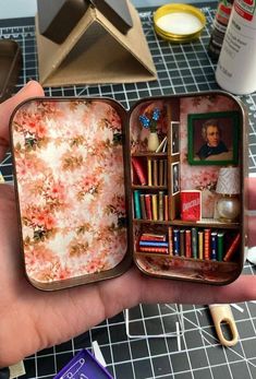 a hand holding an open tint box filled with books