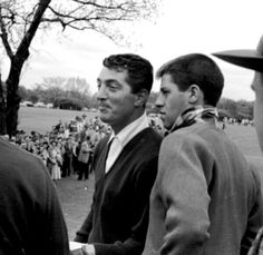 black and white photograph of two men shaking hands in front of a large group of people