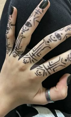 a woman's hand with tattoos on it and two fingers that have writing on them