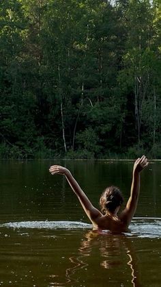 a woman in the water reaching up to catch a frisbee