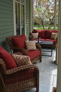 a porch with wicker furniture and red cushions