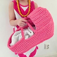 a woman holding a pink crocheted purse