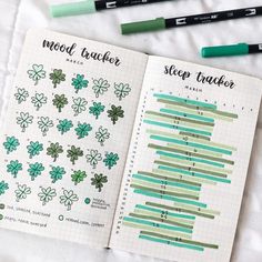 an open planner book with green markers and stickers on it next to some pens